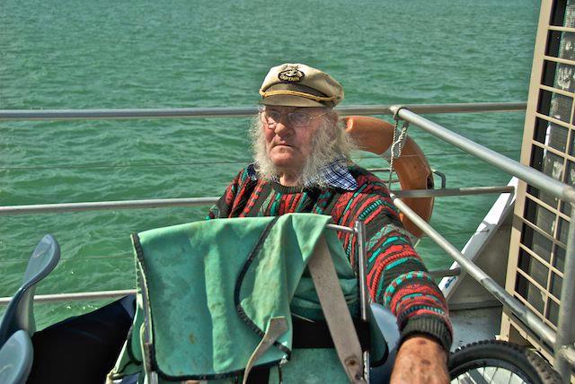 Véronique Cornille; Ron John Pellowe, wearing his Captain cap on Waiheke Island ferry; Lives in pensioner flat on Waiheke Island.  He had been over to visit a sick friend in Pt Chev. He used to hitch hike all around NZ with his green canvas backpack, with a friend, fishing.  His friend has died so he doesn't do that any more and has got rid of all his fishing gear.