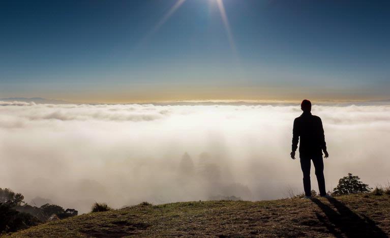Jamie Marr;Stand Alone;A man in prayer on Mt Eden with a fog covered Auckland