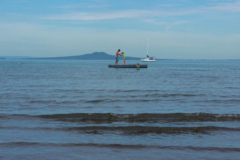 Kim Lane; Pontoon Fun; Arkles Bay beach early in 2014, with Rangitoto looming in the background.