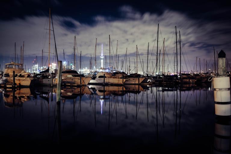 Mylene Villafuerte;Reflection of the City;The photograph was taken at Westhaven, Auckland City using Fujifilm xt10 18 55mm lens. The photo is trying to capture the Auckland city by night by emphasizing the sailing boats and the iconic sky tower.