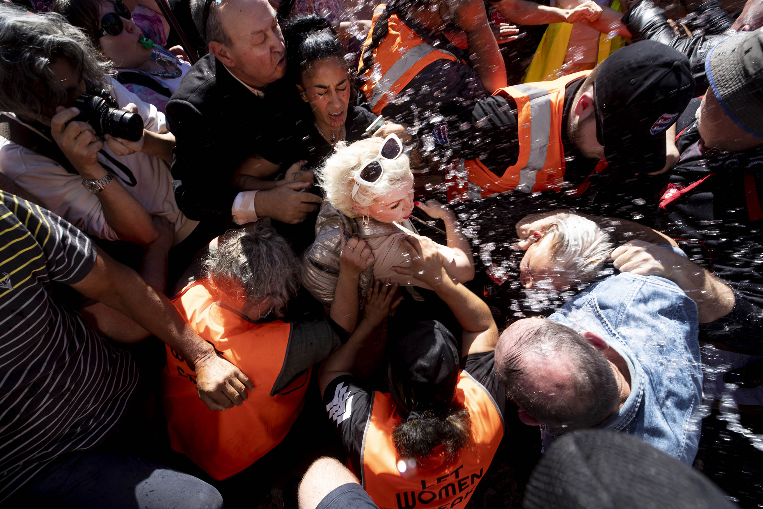 Dean Purcell, British activist Kellie-Jay Keen-Minshull aka Posie Parker is escorted from Albert Park where she was holding a rally as trans-rights supporters try and attack her. 25 March 2023 New Zealand Herald photograph.