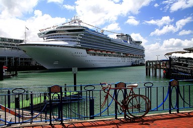 Dawn McKenzie; Two modes of Transport; Here we have the visiting Sapphire Princess and in the foreground another mode of transport not so luxurious.. the bike..strapped to the fence, with one wheel removed incase its stolen.